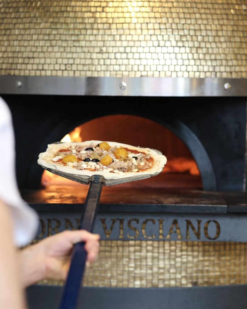 Enfournement d’une pizza dans le four à bois Forni Visciano