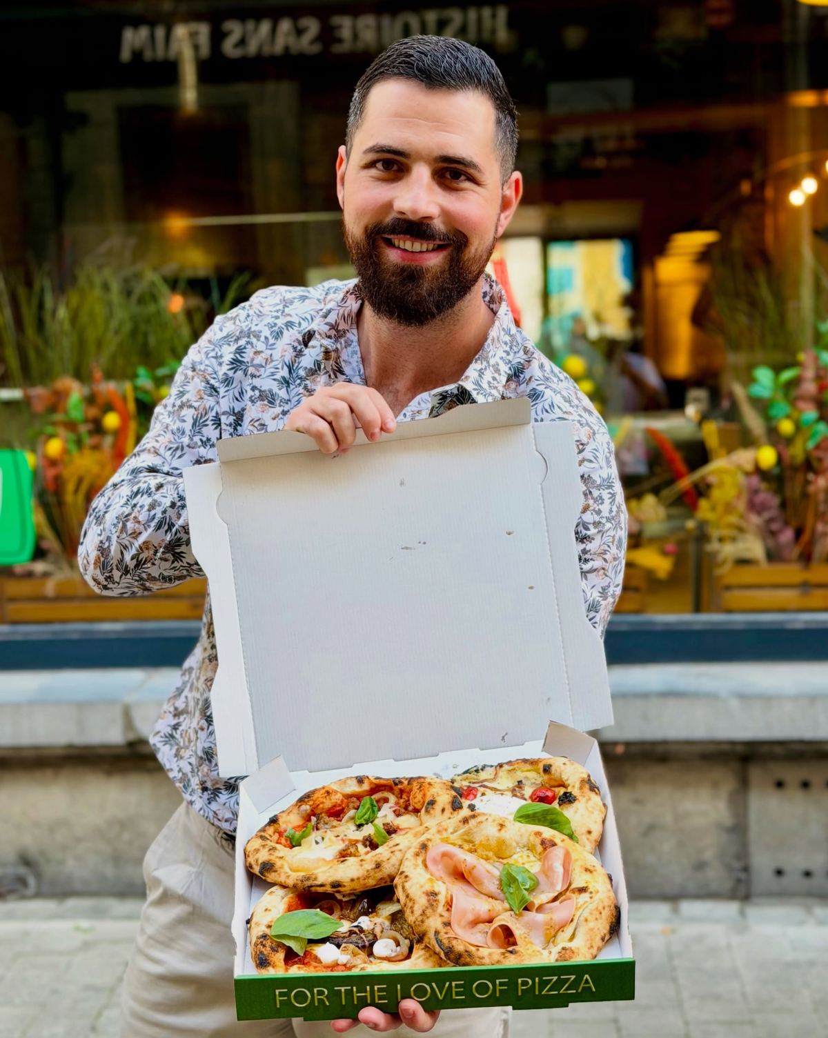Devant la façade de Marghè 2.0, boîte de pizza à emporter en main